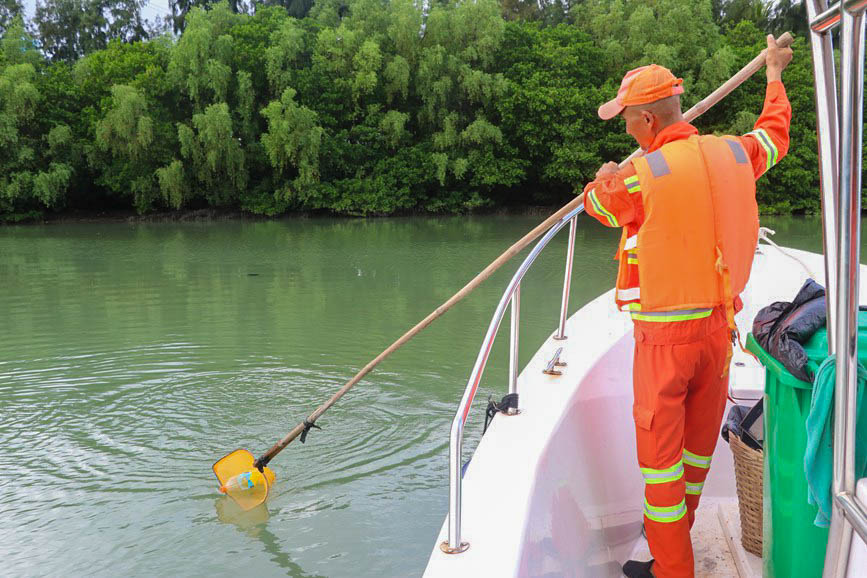 海甸溪海域,数名保洁员乘着环卫船进行海上垃圾打捞工作,将捞上来的