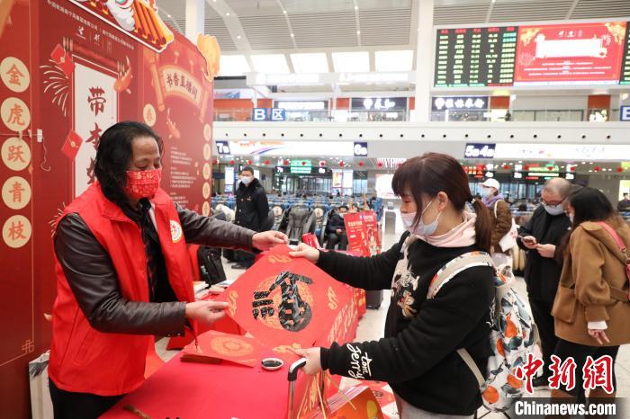 图为柳州火车站“春运书市”书法家为旅客现场送“福”。　卢诗宇 摄