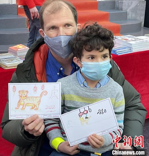 小朋友和家长展示手写手绘的虎年明信片。　德永健 摄