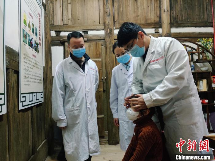图为：“周氏喉科外治法”第六代、第七代传承人正在为患者看诊、推拿。　叶秋云 摄