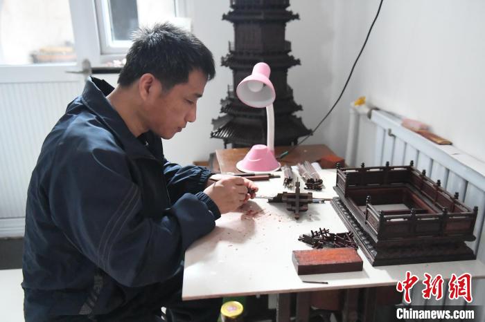 图为李长久正在制作的红木古建筑模型。　张艺典 摄