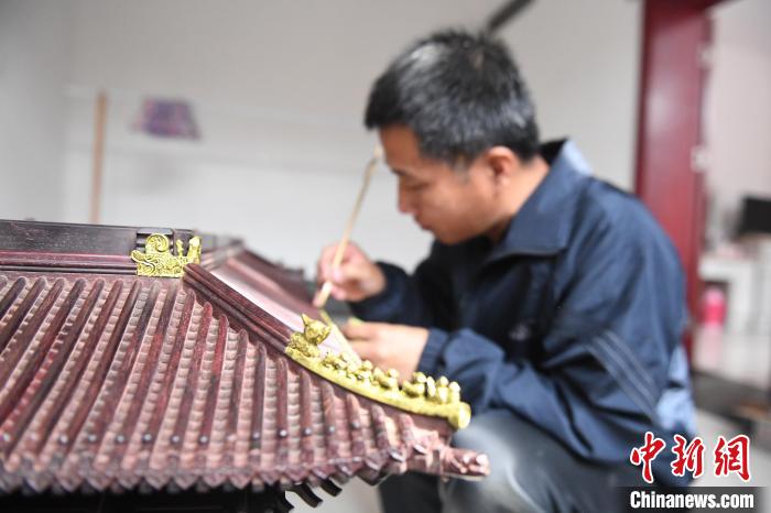 图为李长久在为古建模型作品添涂金箔。　张艺典 摄